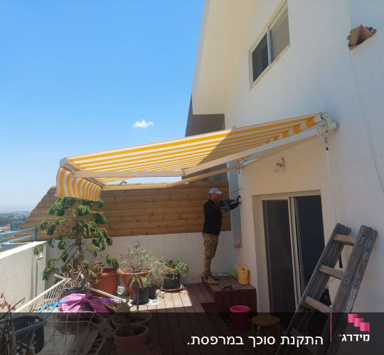 סוכך פסים צהוב-לבן מותקן על קיר חיצוני